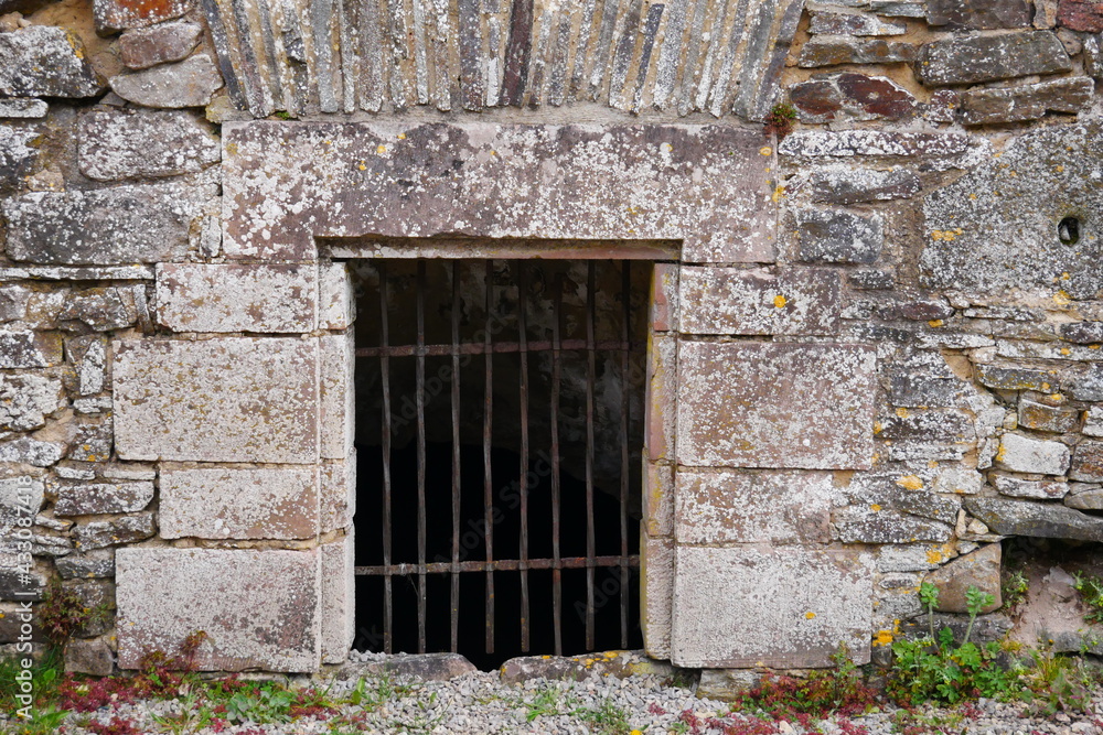 Barred entrance to a dungeon in the medieval wall of an old castle ruin