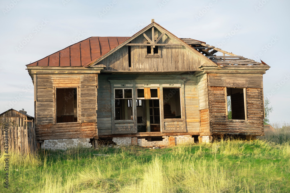 Poor wooden dilapidated house against the sky, surrounded by greenery. Poor wooden dilapidated house against the sky, surrounded by greenery.