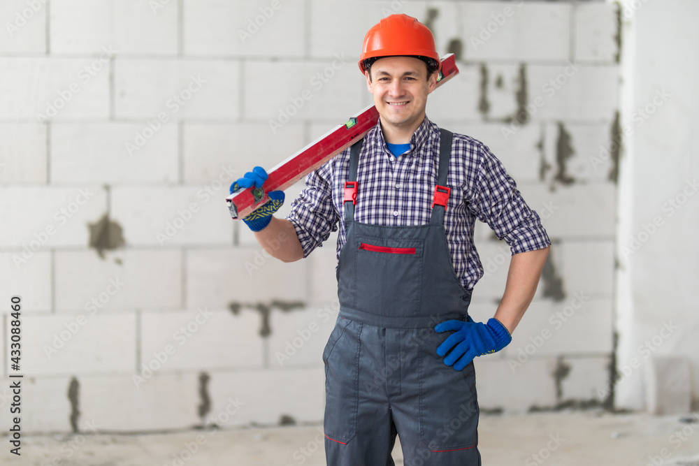 Young handyman holding water level and checking the adjustment to a wall surface Young handyman holding water level and checking the adjustment to a wall surface