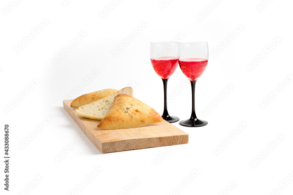 artisanal bread buns on wooden board with wine glasses isolated on white