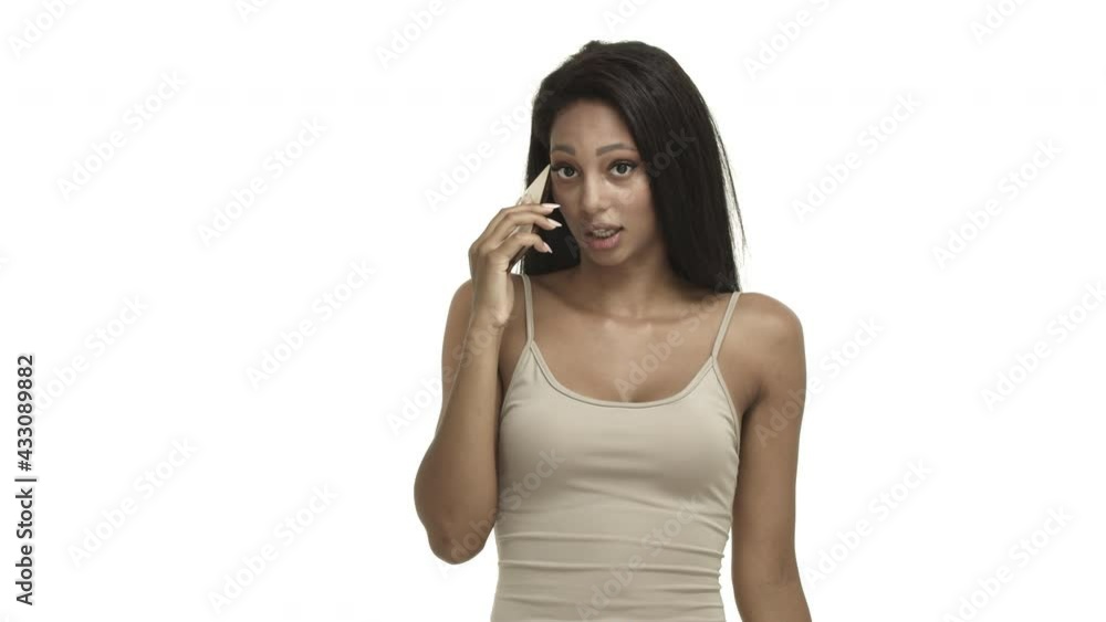 Attractive stylish african-american woman in tank-top, talking on mobile phone, nodding in approval and speaking, standing over white background