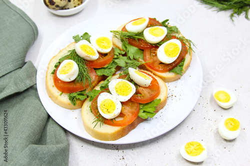 Fresh toast sandwiches with quail eggs, tomatoes and green herbs. Closeup. Top view. Copy space.