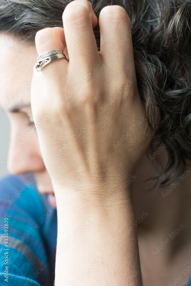 Obraz premium 40 year old woman touching graying curly hair; female embracing natural hair color going dye free