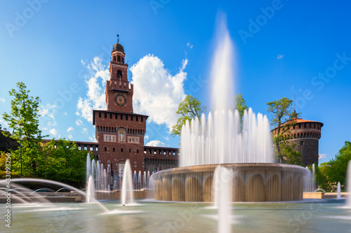 Main entrance to the Sforza Castle - Sforzesco castle and fountain in front of it,long exposure photo, sunny day and clouds in the sky,Milan, Italy photo
