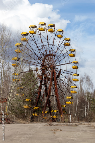 Old abandoned rusty metal radioactive yellow ferris wheel against dramatic sky in amusement park in ghost town Pripyat, Chernobyl Exclusion Zone