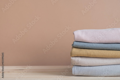 Folded stack clothes on pastel beige background. Fashion, shopping and sale concept. Copy space, close up