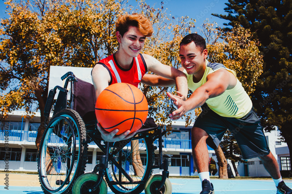 Obraz premium mexican man using wheelchair and playing basketball with a mexican friend in a disability concept