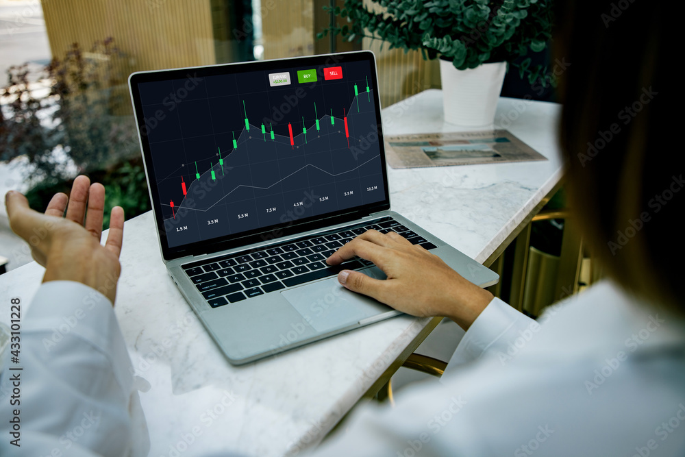 Back view of business woman sitting at desktop front laptop computer with financial graphs and statistics on screen. Successful trader and analyzing data freelance concept. Back view of business woman sitting at desktop front laptop computer with financial graphs and statistics on screen. Successful trader and analyzing data freelance concept.