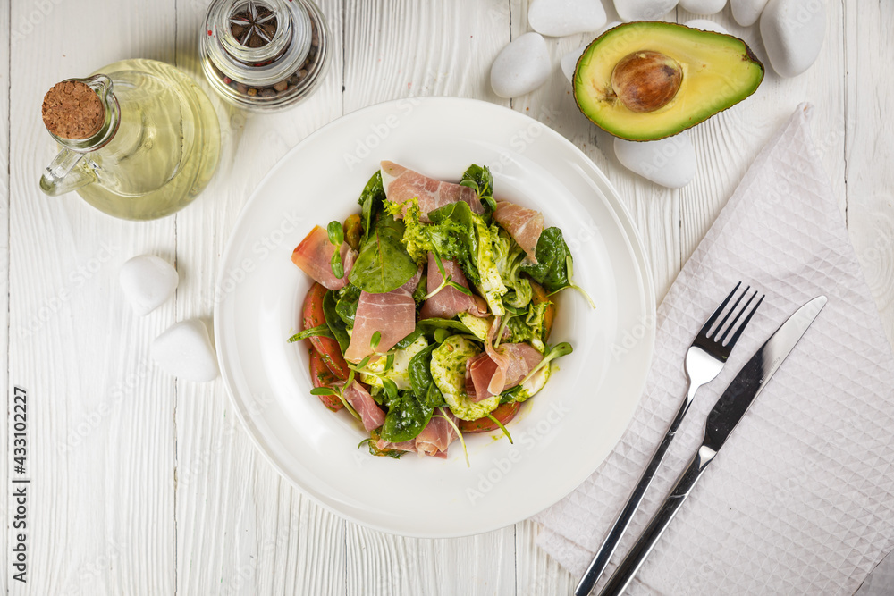 Salad with parma, mozzarella, tomatoes and greens. On a white plate and white table.
Salad with parma, mozzarella, tomatoes and greens. On a white plate and white table.