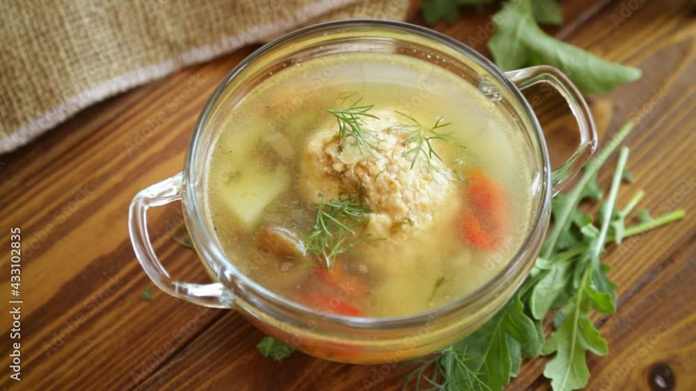 fresh hot soup with chicken meatballs and vegetables in a plate on a wooden table fresh hot soup with chicken meatballs and vegetables in a plate on a wooden table