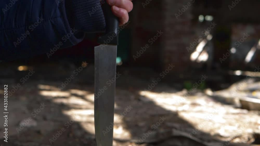 Criminal brings down knife in the shadows of derelict building Criminal brings down knife in the shadows of derelict building