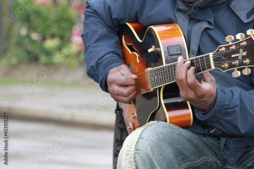 A busking guitarist plays a tune on a semi-electric acoustic guitar in London photo
