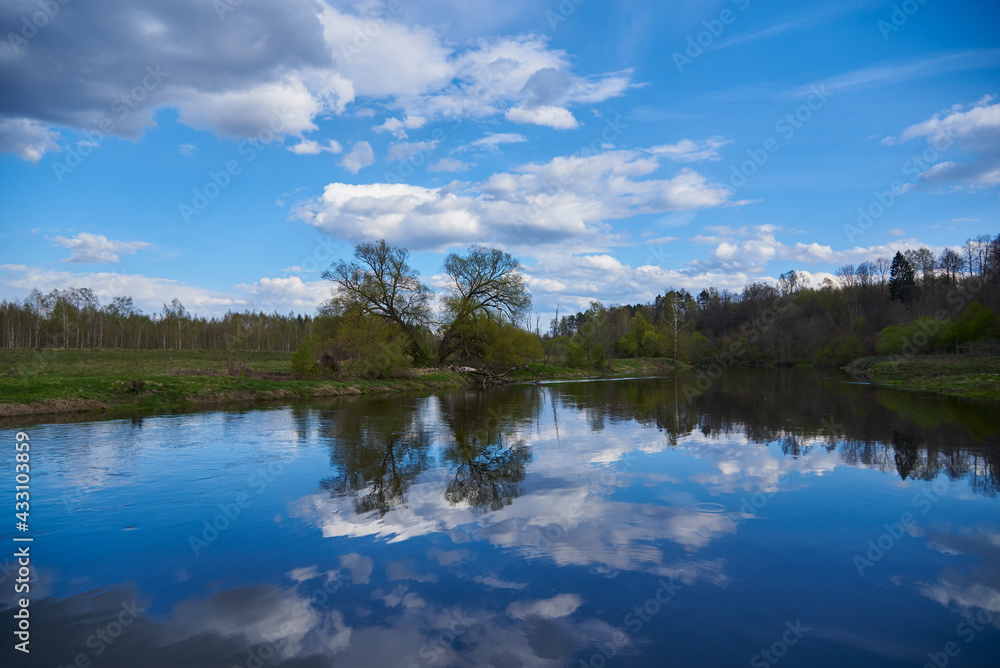 Bright spring landscape.The river flows among the green banks. Bright spring landscape.The river flows among the green banks.