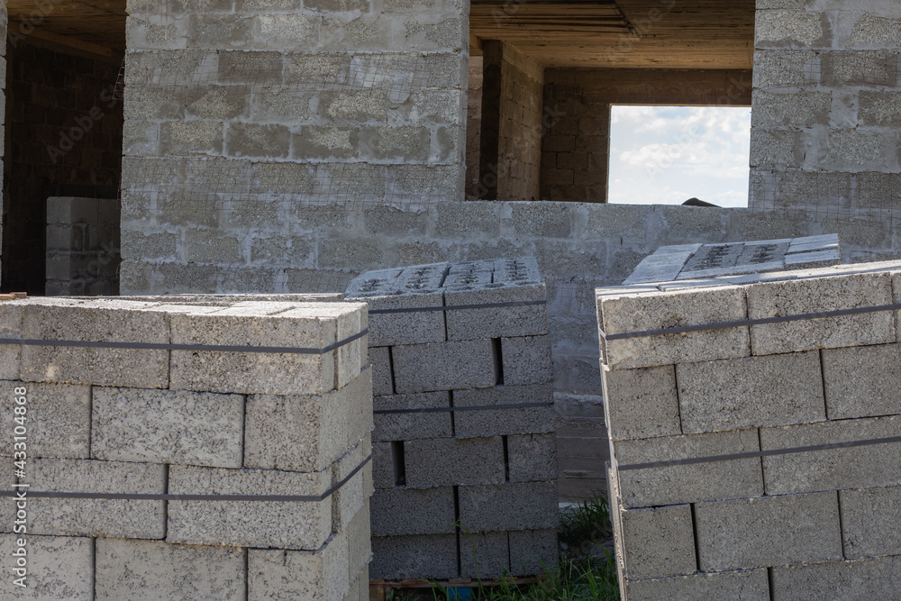 Construction of a private house from cinder blocks. Bundles of gray blocks on pallets at a construction site Construction of a private house from cinder blocks. Bundles of gray blocks on pallets at a construction site
