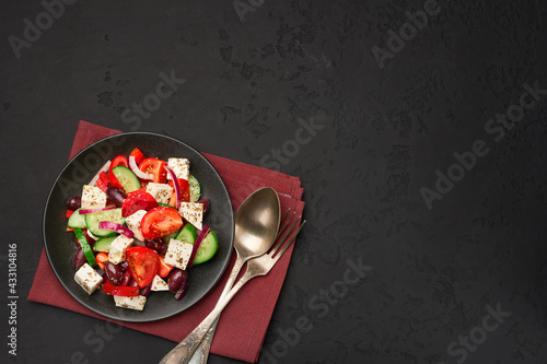 Classic greek salad in a plate top view on a dark background with copy space