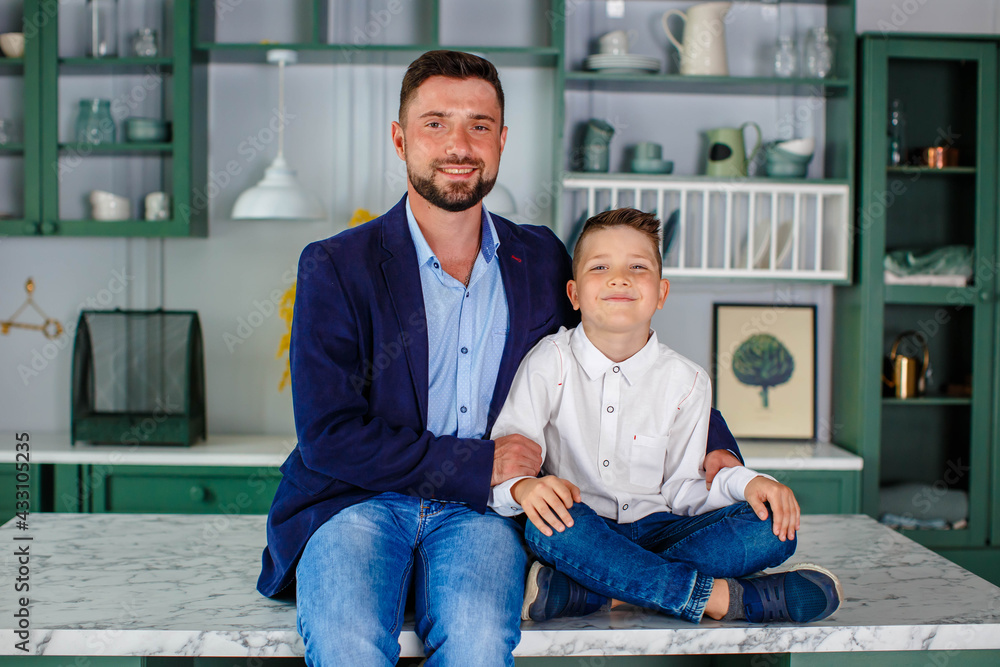 Father and son spend time in the kitchen, having breakfast on the background of a green kitchen. Sit on the kitchen table Father and son spend time in the kitchen, having breakfast on the background of a green kitchen. Sit on the kitchen table