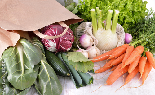 vegetables in a reusable  and paper bags among other  fresh vegetables
