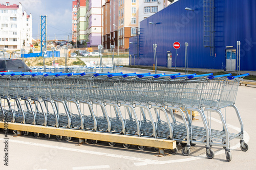 Many empty blue metal carts for shopping in a supermarket parking