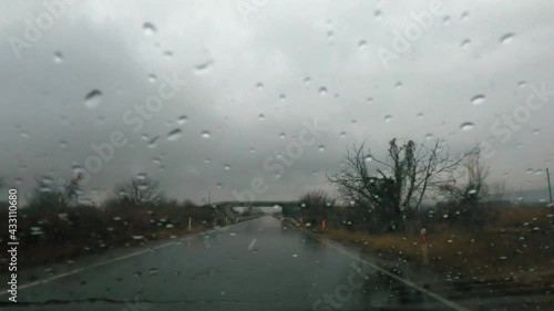 Driver POV of the windshield on the sports car with rain drops, driving on the heavy rain photo