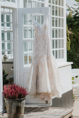 an expensive and beautiful wedding dress hangs on the door