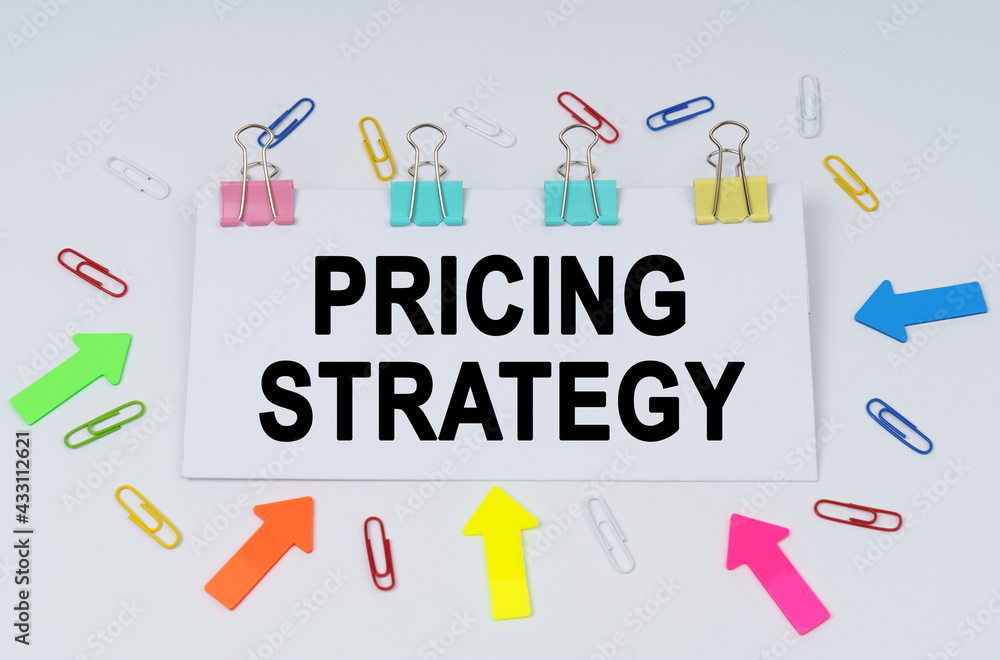 On the table there are paper clips and directional arrows, a sign that says - Pricing Strategy On the table there are paper clips and directional arrows, a sign that says - Pricing Strategy