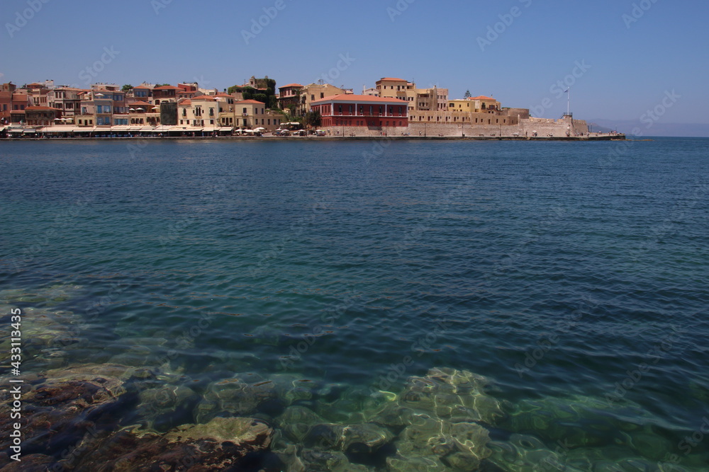 A landscape of a harbour with buildings and rocks under the sea