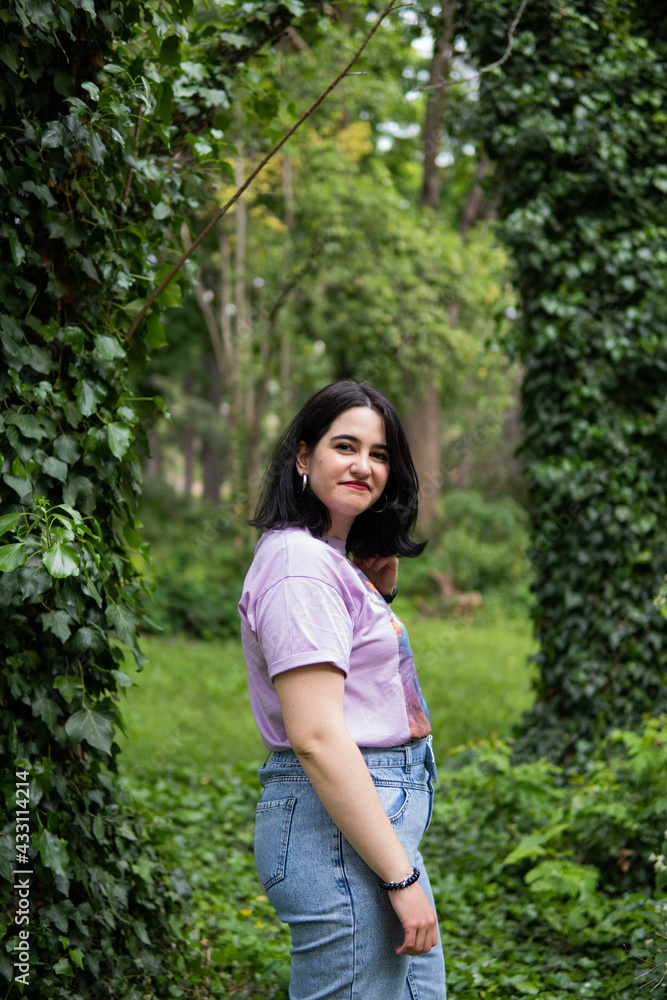 Photo of an attractive woman with black hair in the middle of nature during spring time, walking around and smiling during a sunny day Photo of an attractive woman with black hair in the middle of nature during spring time, walking around and smiling during a sunny day