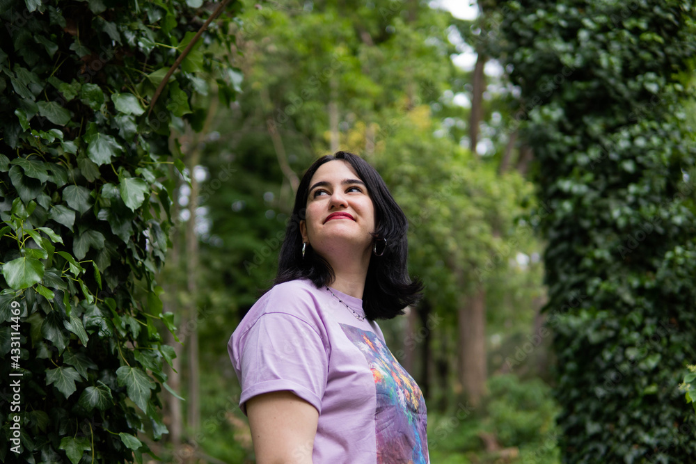 Photo of an attractive woman with black hair in the middle of nature during spring time, walking around and smiling during a sunny day Photo of an attractive woman with black hair in the middle of nature during spring time, walking around and smiling during a sunny day