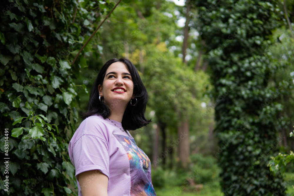 Photo of an attractive woman with black hair in the middle of nature during spring time, walking around and smiling during a sunny day Photo of an attractive woman with black hair in the middle of nature during spring time, walking around and smiling during a sunny day