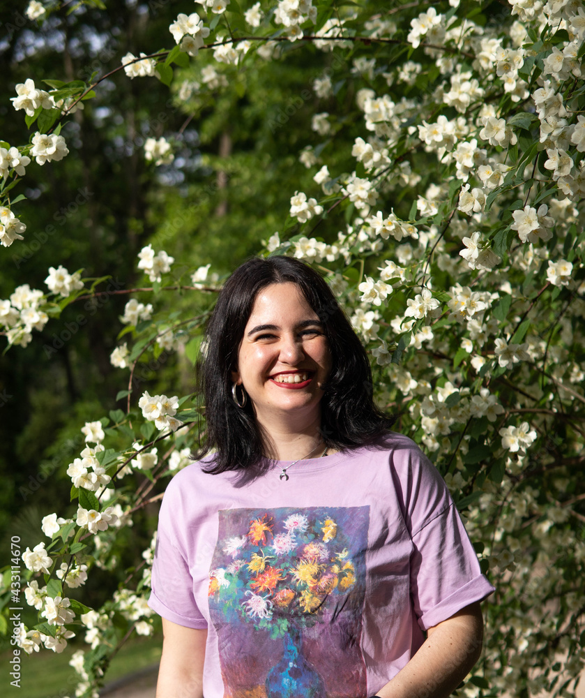 Photo of an attractive woman with black hair in the middle of nature during spring time, walking around and smiling during a sunny day Photo of an attractive woman with black hair in the middle of nature during spring time, walking around and smiling during a sunny day
