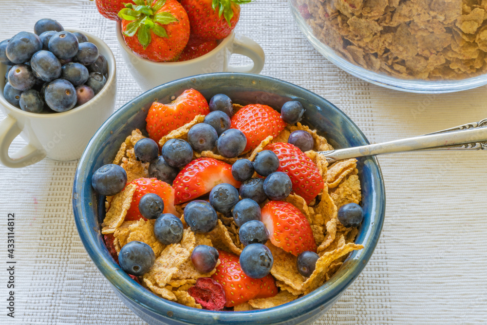 fresh strawberries and blueberries in cornflakes in blue bowl fresh strawberries and blueberries in cornflakes in blue bowl