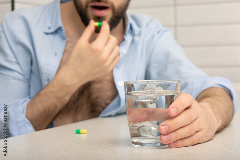 Bearded man has insomnia, man takes sleeping pills, glass of water, close-up, cropped image Bearded man has insomnia, man takes sleeping pills, glass of water, close-up, cropped image