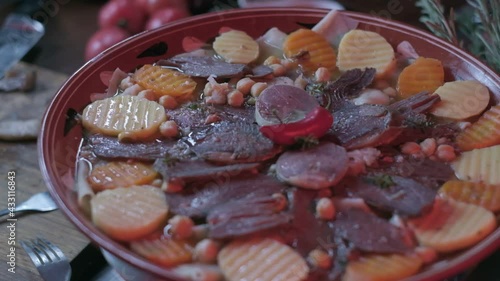 Close-up of national Kazakh dish Beshbarmak made of veggies, dough and horsemeat served in deep clay dish with hot red pepper on top photo