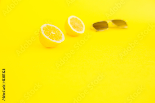 Two halves of lemon on neon yellow color and sunglasses. It's summer, enjoy. Summer is coming. Minimalist photo showing the serenity of flight. Self-care and eat summer fruit. .