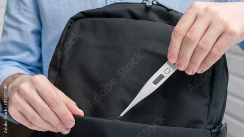 Wallpaper Mural Person puts electronic thermometer in a backpack, male hands, cropped image, close-up Torontodigital.ca