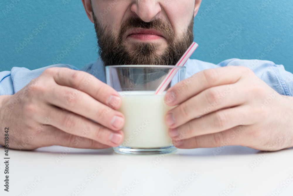 dissatisfied man with glass of milk with a straw, cropped image