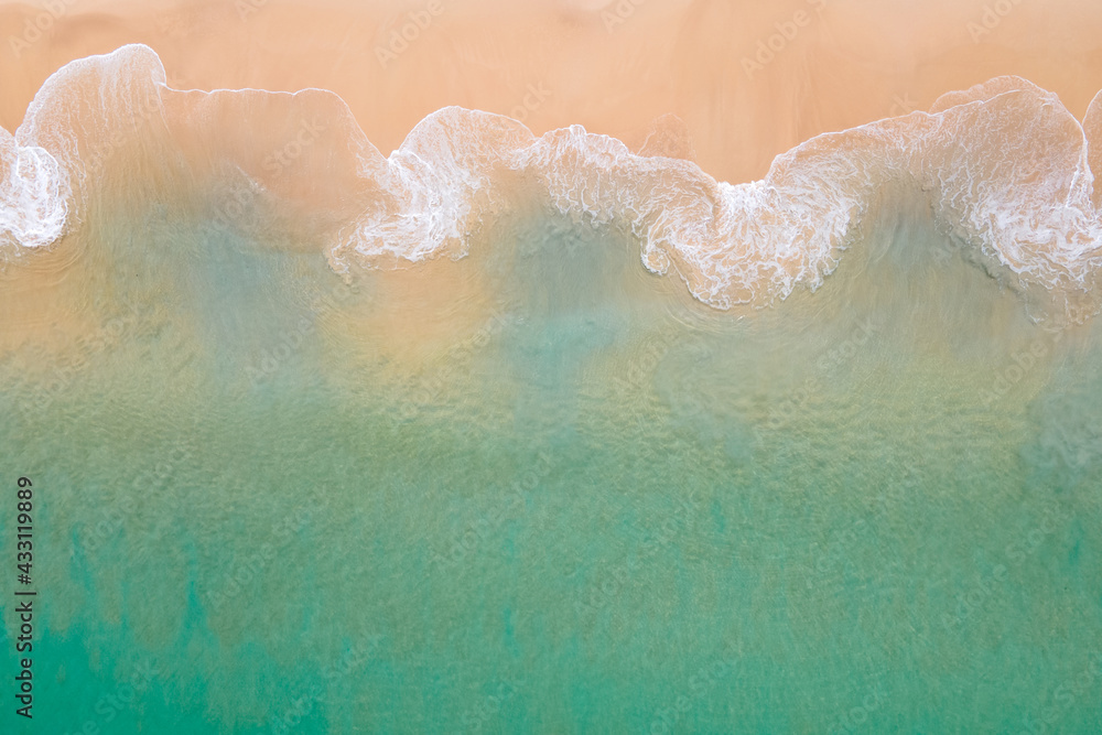 Fototapeta premium Aerial view of turquoise ocean wave reaching the coastline. Beautiful tropical beach from top view. Andaman sea in Thailand. Summer holiday vacation concept