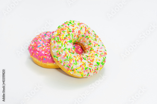 Two tasty donut with bright sprinkles, white background, side view, copy space