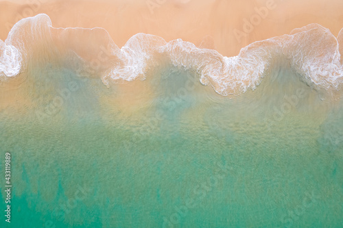 Aerial view of turquoise ocean wave reaching the coastline. Beautiful tropical beach from top view. Andaman sea in Thailand. Summer holiday vacation concept