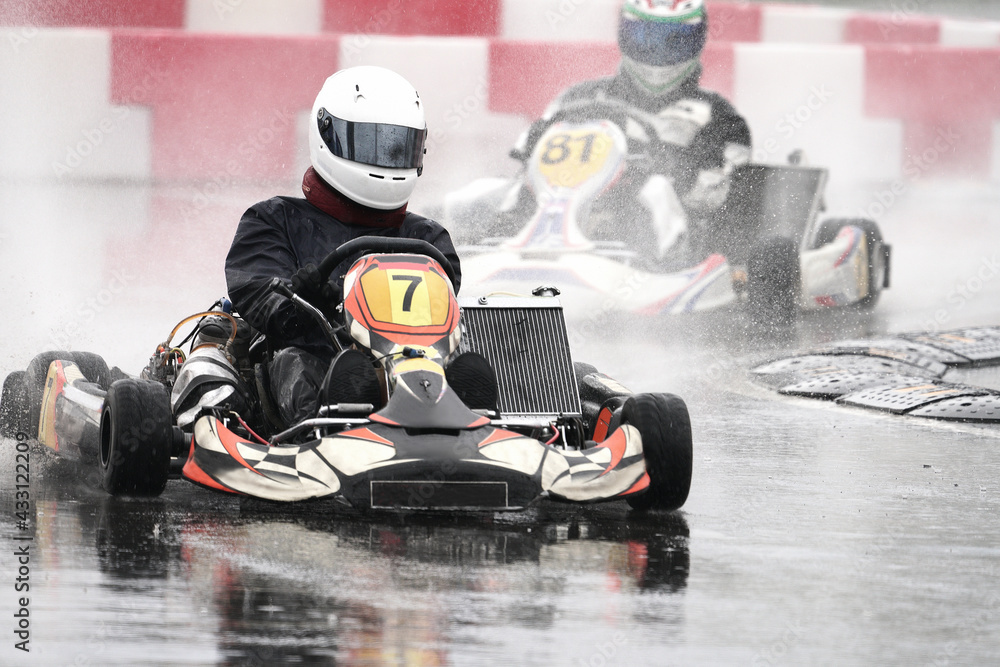 Sports car racing. Two racing cars at speed enter the turn. It's raining. Spray is flying from under the wheels of the karts. Selective focus. Blur in motion. Copy space.