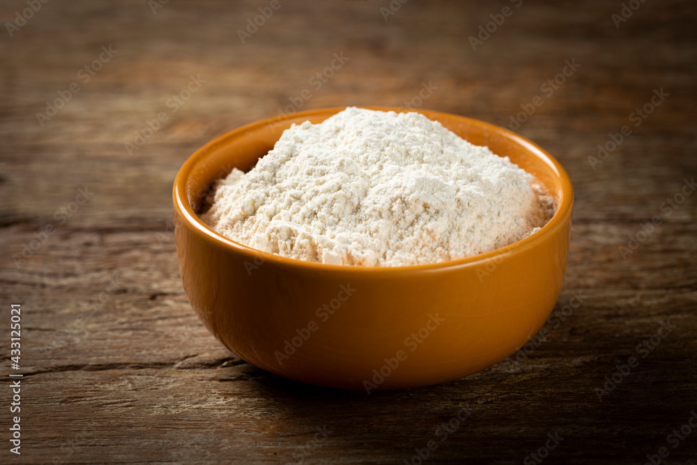 Bowl with wheat flour on the table.