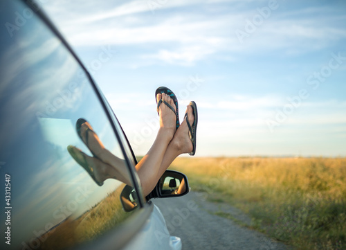 Fotografie Girl sticking her feet in flip flops out of a car window.