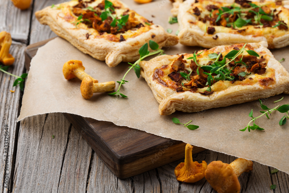 Homemade tarts of puff pastry with seasonal chanterelle mushrooms on rustic table.
