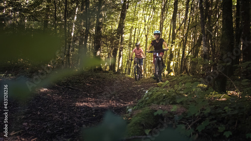 Two girls on mtb bikes. Mother and daughter riding on a forest trail.