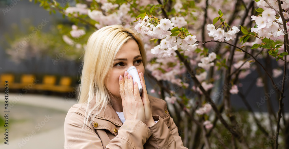 Young pretty girl blowing nose in front of blooming tree. Spring allergy concept Young pretty girl blowing nose in front of blooming tree. Spring allergy concept