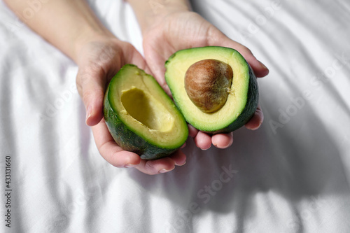 Woman holds a green cut avocado in her hands. Avocado close-up. Natural fresh organic exotic fruits. Healthy food, raw food diet. Vegetarian life. Proper nutrition. Ready to eat. Eco product. Poster