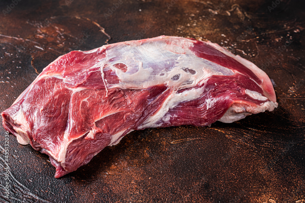 Raw lamb mutton shoulder meat on the bone. Dark background. Top view