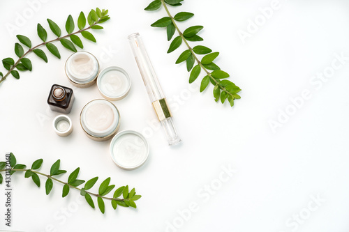 face cosmetics in gold colour, restoring mascara and sprigs of juicy greenery on a white background