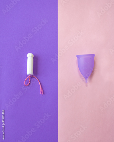 female tampon and purple menstrual cup on a plain bicolor pink and purple background