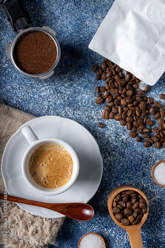 Top view of a cup of coffee, a coffee container, and a pile of coffee beans on a kitchen table - obrazy, fototapety, plakaty 